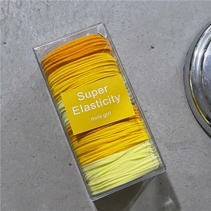 Macro detail of elastic hair ties in orange and yellow shades inside a plastic box