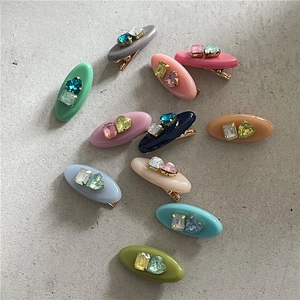 Détail de pinces à cheveux ovales avec strass géométriques en diverses couleurs pastel