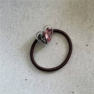 Détail de breloques double cœur en strass sur un élastique à cheveux marron
