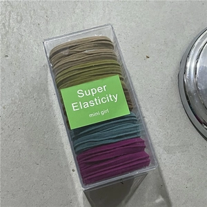Detail of colorful high elasticity hair ties in a transparent box with green card insert