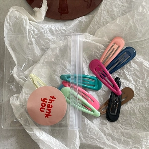 Gros plan de pinces BB colorées en métal émaillé dans un sac avec étiquette merci
