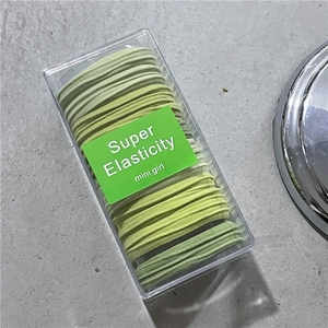 Macro shot of a set of gradient green high elasticity hair ties in a clear plastic box
