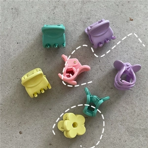 Close-up of assorted macaron colored flower hair clips on a grey textured background