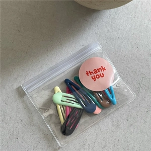 Vue détaillée de dix barrettes goutte colorées aux tons crème dans un emballage cadeau