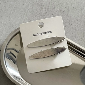 Détail de barrettes en métal argenté brossé sur un plateau minimaliste en inox chic