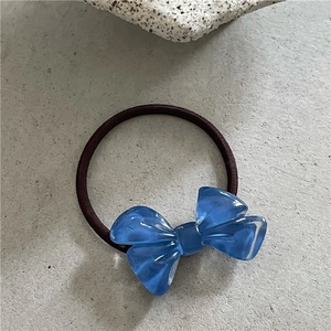 Detail eines blauen Haargummis mit Harzschleife in Gelee-Optik auf einer Steinplatte