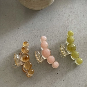 Détail de pinces à cheveux géométriques effet gelée en ambre rose et vert pastel