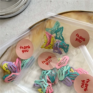Close-up of colorful polka dot BB hair clips in clear packaging with thank you stickers