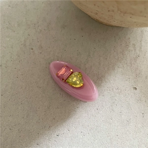Détail d'une pince à cheveux ovale rose avec strass carrés et en forme de cœur