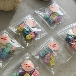 Close-up of pastel flower hair clips in transparent bags with pink thank you stickers
