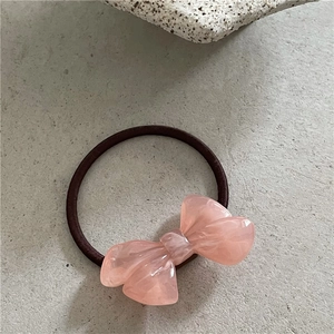 Nahaufnahme von rosa marmoriertem Harz-Haargummi mit braunem elastischem Seil-Detail