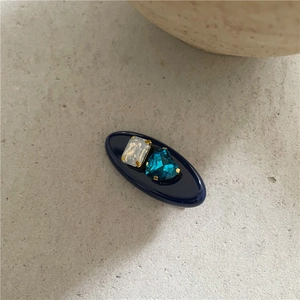 Détail de la barrette ovale bleu foncé avec zircon rectangulaire et gemme en cœur