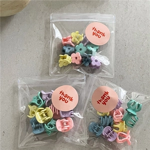 Macro view of assorted macaron flower mini hair clips in individual thank you bags