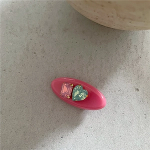 Détail d'une barrette en résine rose avec pierre rectangulaire violette et cœur bleu