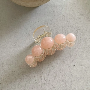 Détail de la pince à cheveux en résine jaune avec des perles effet marbre rose