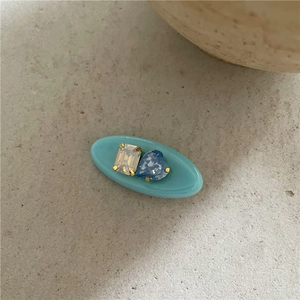 Détail d'une pince à cheveux en résine bleue avec strass en cœur et griffes dorées