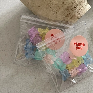 Macro shot of colorful mini flower hair claws in macaron tones within a clear gift package