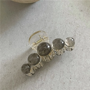 Détail de la pince à cheveux avec perles marbrées grises et ressort en métal doré