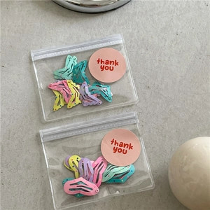 Macro view of colorful polka dot macaron hair clips in clear gift bag with pink sticker
