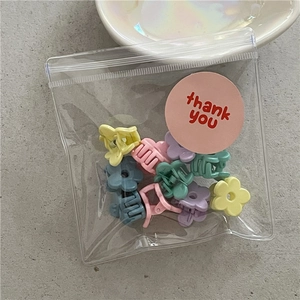 Detail of colorful mini flower hair claws in macaron shades inside a clear zip bag
