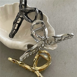 Close-up of liquid metal hair claws in gold, silver and gunmetal finish on a tray