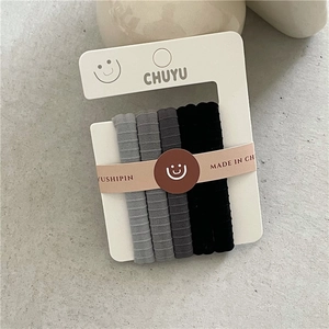Gros plan de quatre élastiques à cheveux dégradés gris et noir sur support