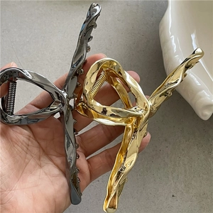 Sleek liquid metal alloy hair claws in gold and silver finish with twisted design