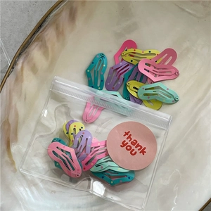 Colorful heart-shaped polka dot hair clips set in a clear pouch on a marble tray