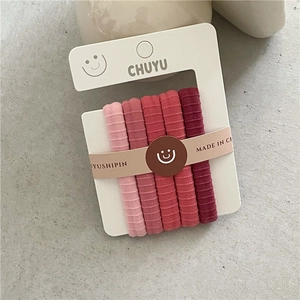 Détail de cinq chouchous élastiques dégradés de rose présentés sur carte blanche