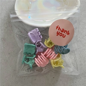 Detail view of 10-piece macaron-colored flower hair claws in clear thank-you packaging