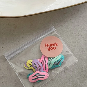 Detailed view of colorful polka dot metal hair clips in a transparent thank you gift bag
