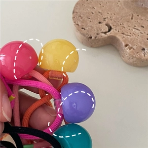 Close-up of colorful elastic hair bands with glossy sphere charms in cream tones