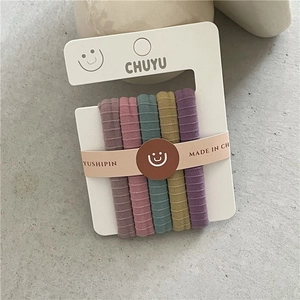 Détail de cinq élastiques à cheveux aux couleurs Morandi avec texture à côtes sur carte