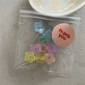 Detailed view of macaron flower hair clips in transparent zip bag with a thank you sticker