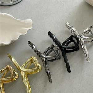 Macro shot showing four liquid metal hair claws in gold, silver, black, and gunmetal gray