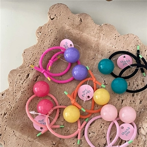 Close-up of colorful jelly bead hair ties with thank you tags on a stone texture background