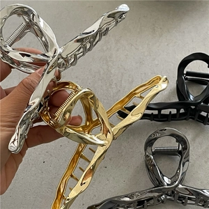 Detail showing the large alloy hair claw clips in gold, silver, black, and gunmetal finishes