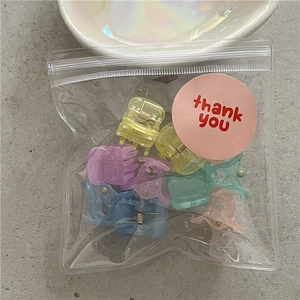 Close-up of colorful mini flower hair claws set in clear packaging with a thank you sticker