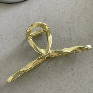 Close-up of golden liquid metal hair claw clip with twisted alloy texture and strong spring