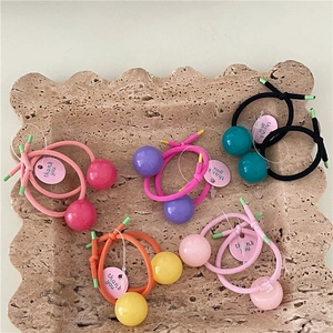 Detailed view of colorful elastic hair ties with glossy beads on a stone tray