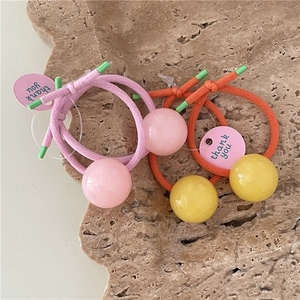 Detail of jelly bead hair ties with thank you tags on a textured stone surface