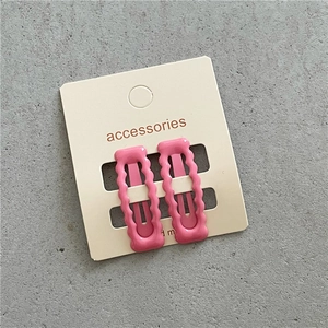 Detailsicht zweier rosa gewellter rechteckiger Haarspangen auf einer Displaykarte