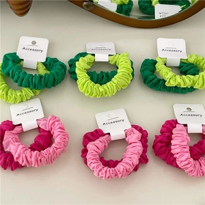 Two-piece scrunchie sets in vibrant green and pink fabric on a display card