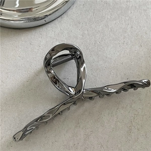 Detailed macro view of gunmetal liquid metal hair claw with streamlined twist design