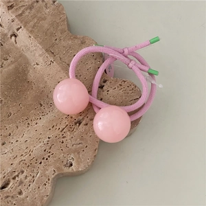 Close-up of pink jelly ball hair ties with woven elastic rope and green accents