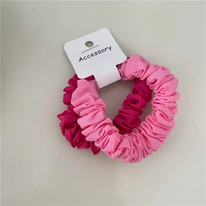 Close-up of two-piece pink pleated fabric hair scrunchies on a white card display
