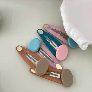 Close-up of oval resin hair clips in assorted colors with engraved metal base