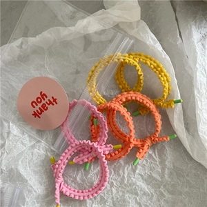 Gros plan de trois chouchous à volants en couleurs vives jaune, orange et rose fluo