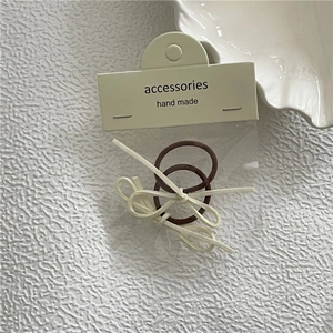 Detailansicht brauner elastischer Haargummis mit cremefarbener Schleife in Verpackung