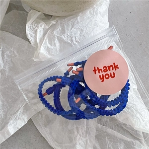 Détail de chouchous bleus à volants sous sachet avec un autocollant rose de merci
